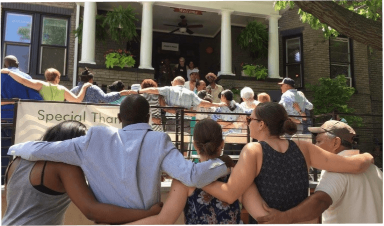 A group of people arm in arm in front of Joseph's House.