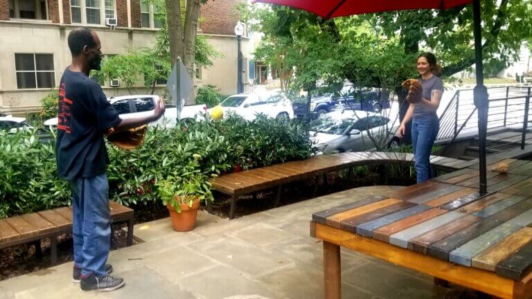 A resident and volunteer playing catch on a patio.